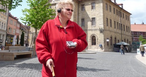 Eine Frau mit Seh-Beeinträchtigung trägt einen Audio-Guide