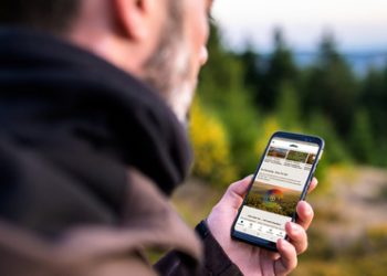 Wanderer im Wald nutzt die Thüringer Wald App auf seinem Handy