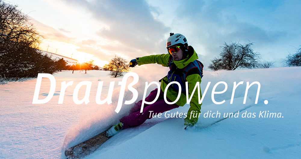 Kampagnenmotiv zum zweiten Kampagnen-Flight. Man sieht einen Alpin-Skifahrer in Thüringer Tiefschneelandschaft. Im Hintergrund ist Sonnenuntergang. Im Bild ist die Aufschrift "Draußpowern. Tue Gutes für dich und das Klima." zu lesen.