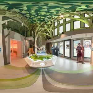 farbliche Gestaltung einer Erlebniswelt in einer Tourist Information mit einem KUKA-Roboter in der Mitte, einzelnen Figur-Aufstellern und einem Baum-Panorama