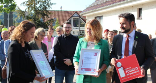 Person übergibt Urkunde als Auszeichnungen für die Touristinformation